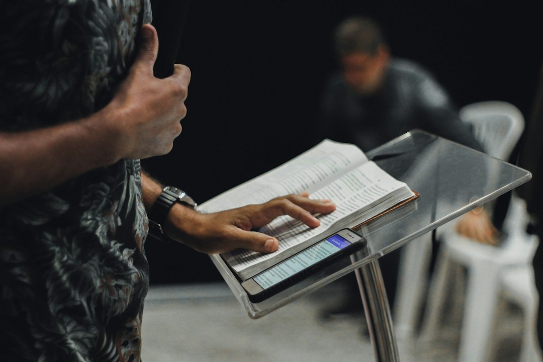 Pregador com livro aberto no palco durante uma mensagem bíblica