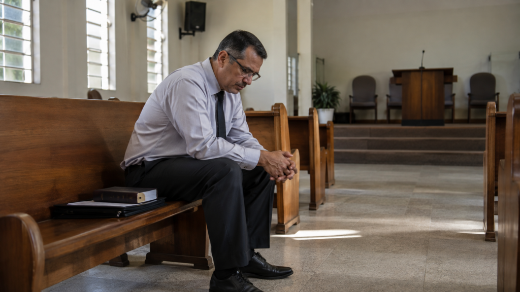 Pastor refletindo sozinho sobre o desgaste e a pressão financeira no ministério.
